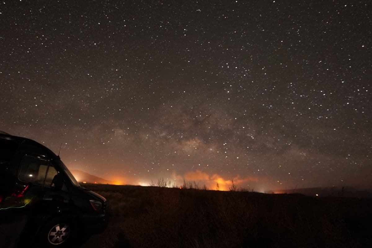 星空の下、遠くで赤く光る火山の明かり