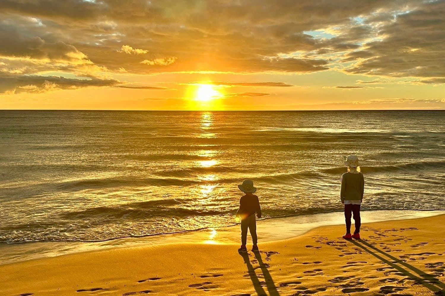 ビーチの波打ち際から眺める、海に沈む夕日